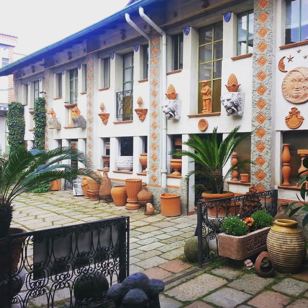 Courtyard of Fornace Curti with terracotta pots and decorated facades