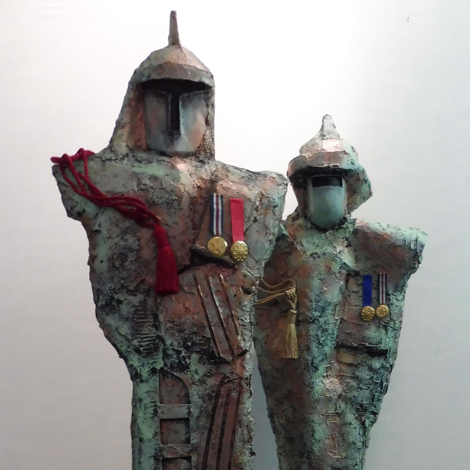 Two Telamoni sculptures by Stefano Iosca, helmeted bronze figures with red ribbons and medals
